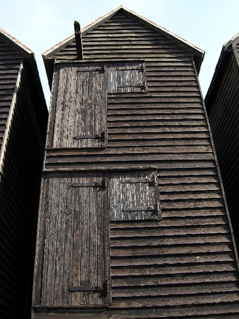A tall black wooden net hut on the Stade, Hastings